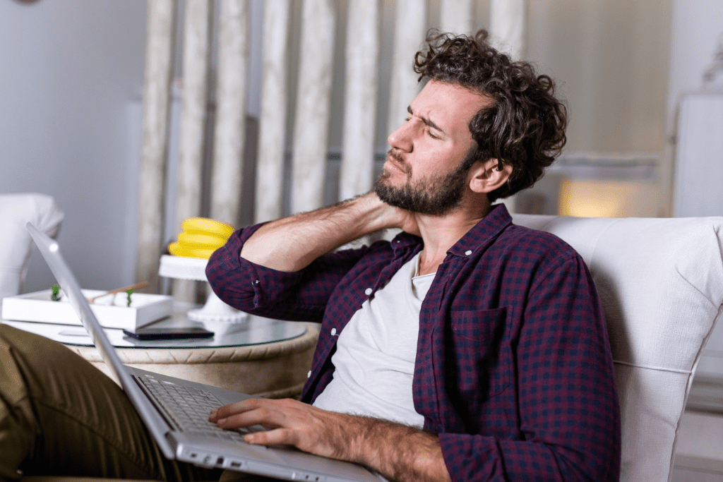 Person experiencing neck pain due to prolonged work on a couch